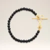 Bracciale Ami De Cœur in ottone nero con perle estive dorate Bracciale Ami De Cœur in ottone nero con perle estive dorate