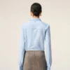 Camicia blu in cotone a maniche lunghe con volant e vestibilità aderente Camicia blu in cotone a maniche lunghe con volant e vestibilità aderente